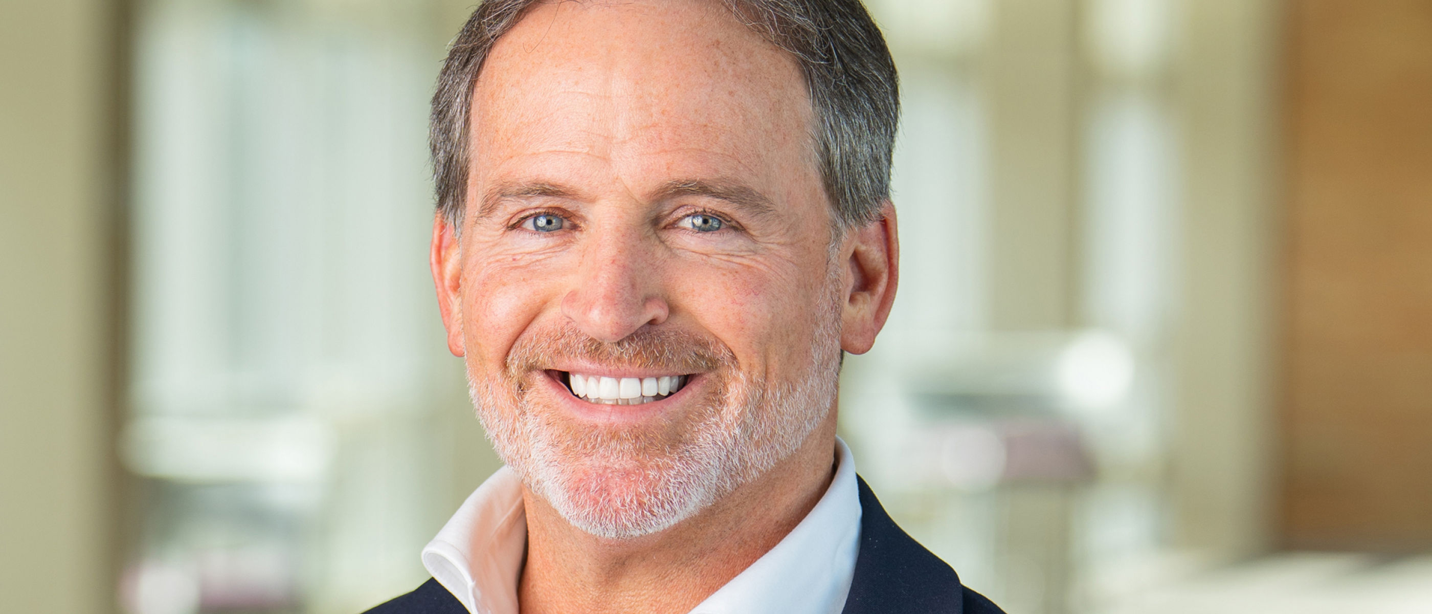 Portrait of a man, Bryan Hanson, Solventum CEO, smiling and wearing a blue jacket and white shirt.