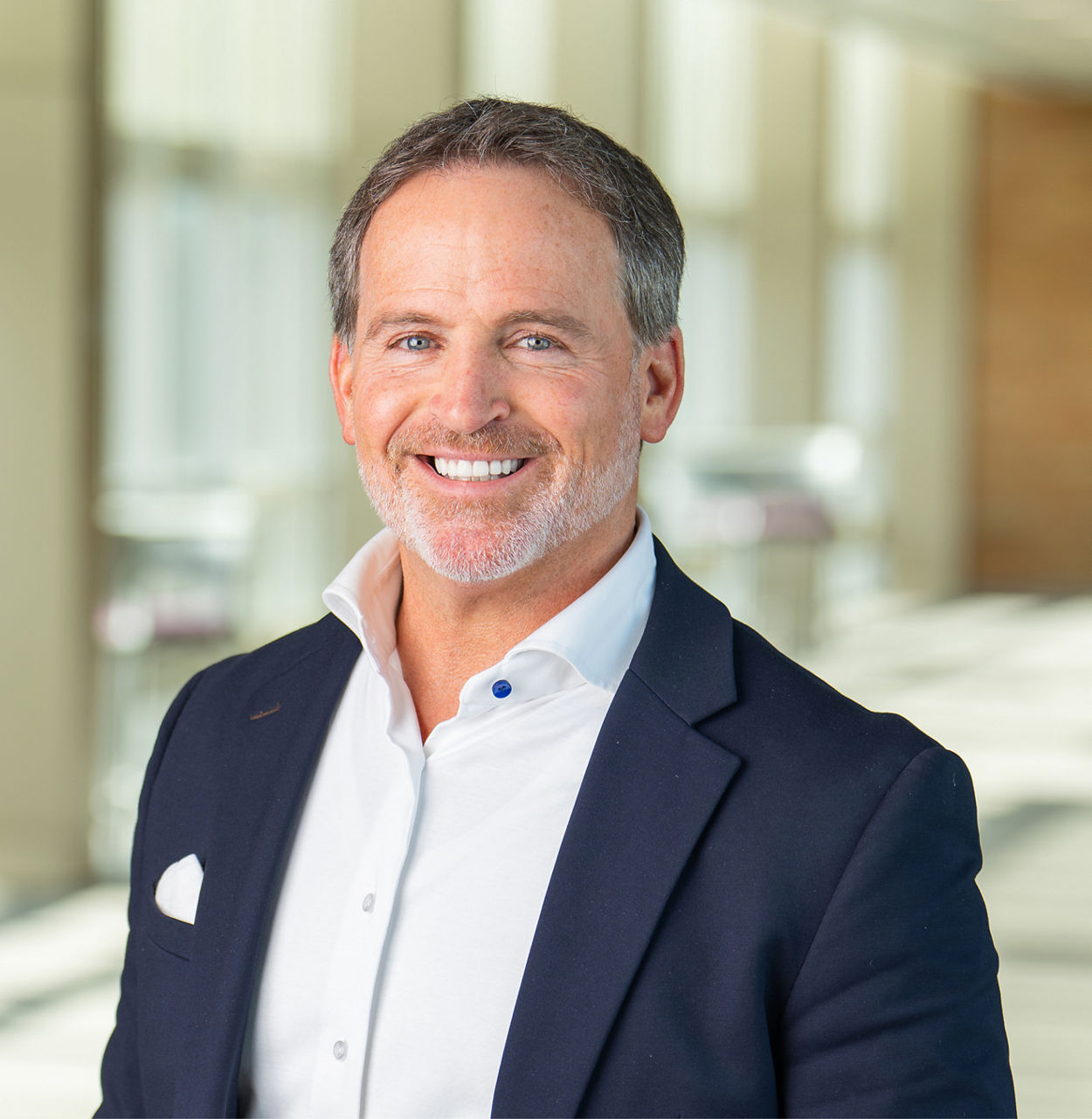 Portræt af en mand, Bryan Hanson, administrerende direktør i Solventum, smilende og iført en blå jakke og hvid skjorte.