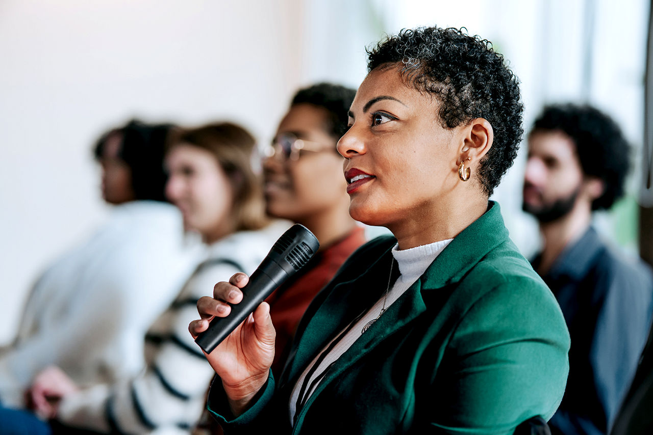 Woman in green jacket speaking at event