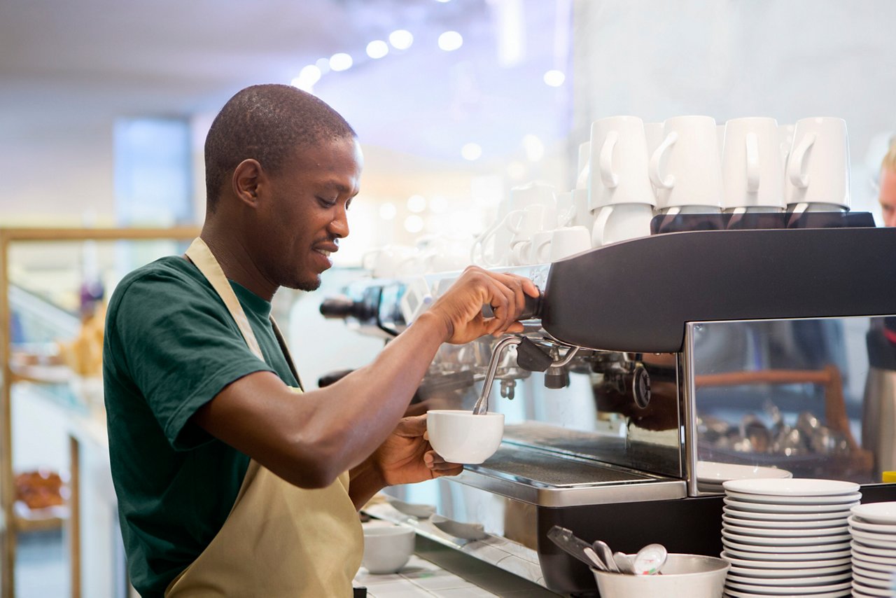 Smiling waiter preparing coffee in coffee shop