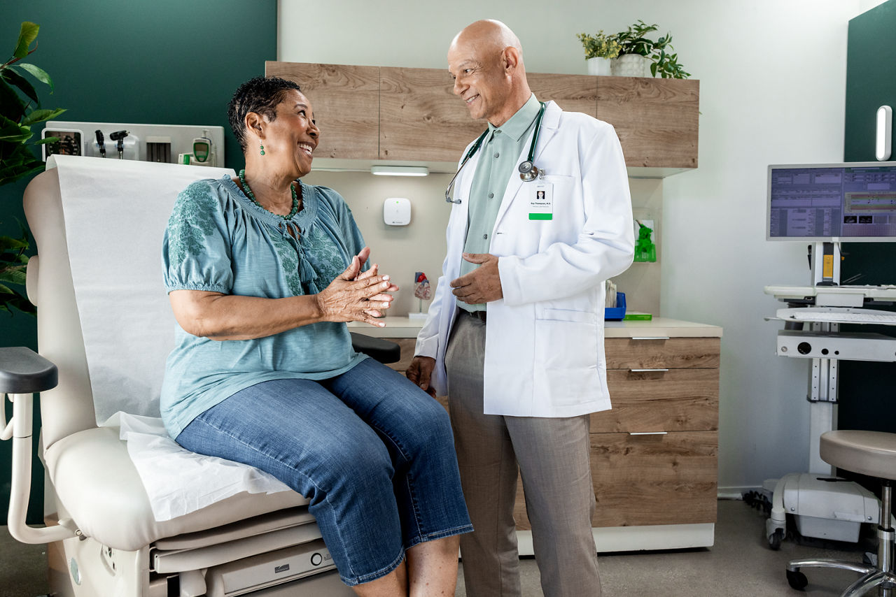 Patiente adulte féminine souriante et interagissant avec un médecin généraliste masculin dans un cabinet de consultation.