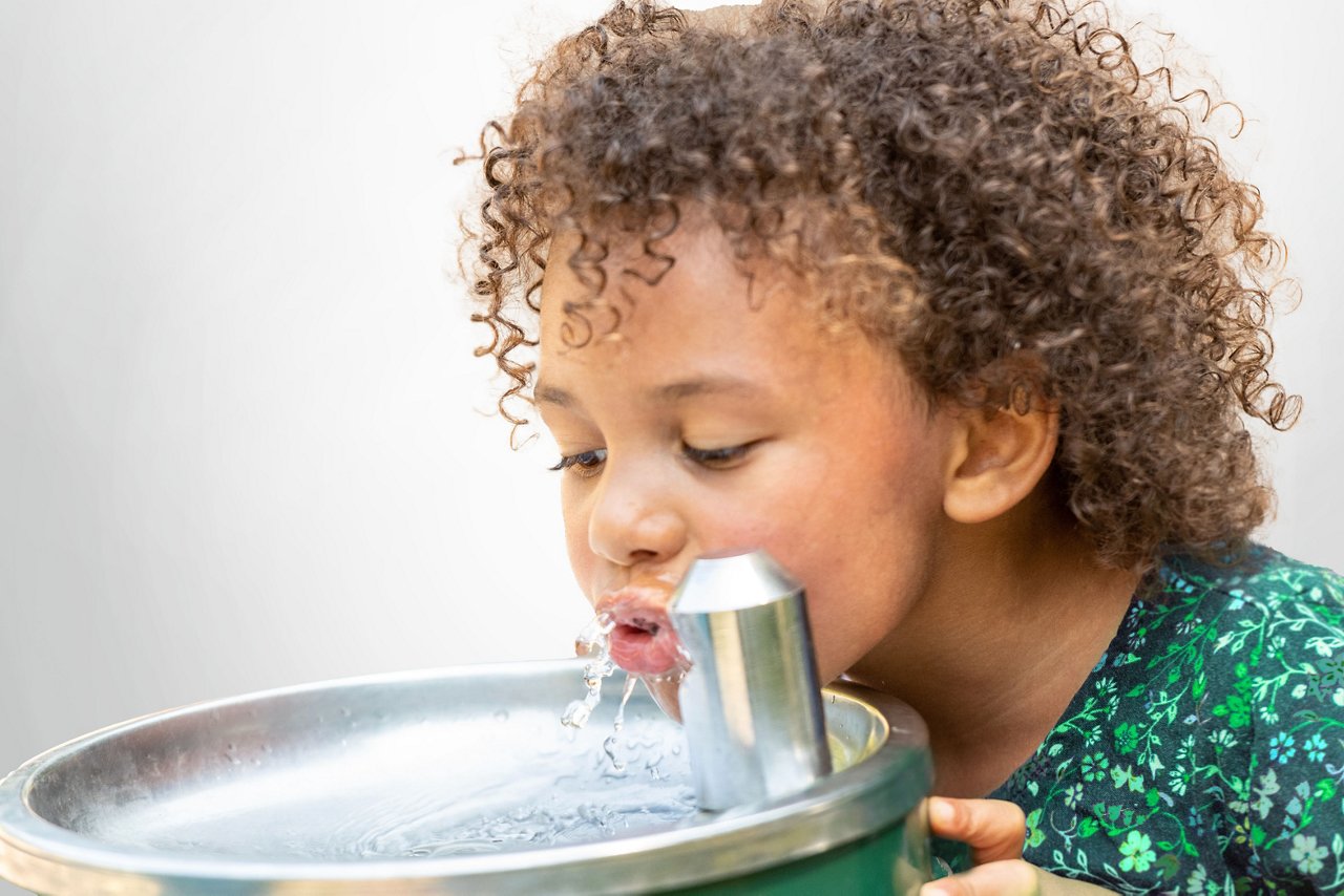 Young girl drinking from water fountain