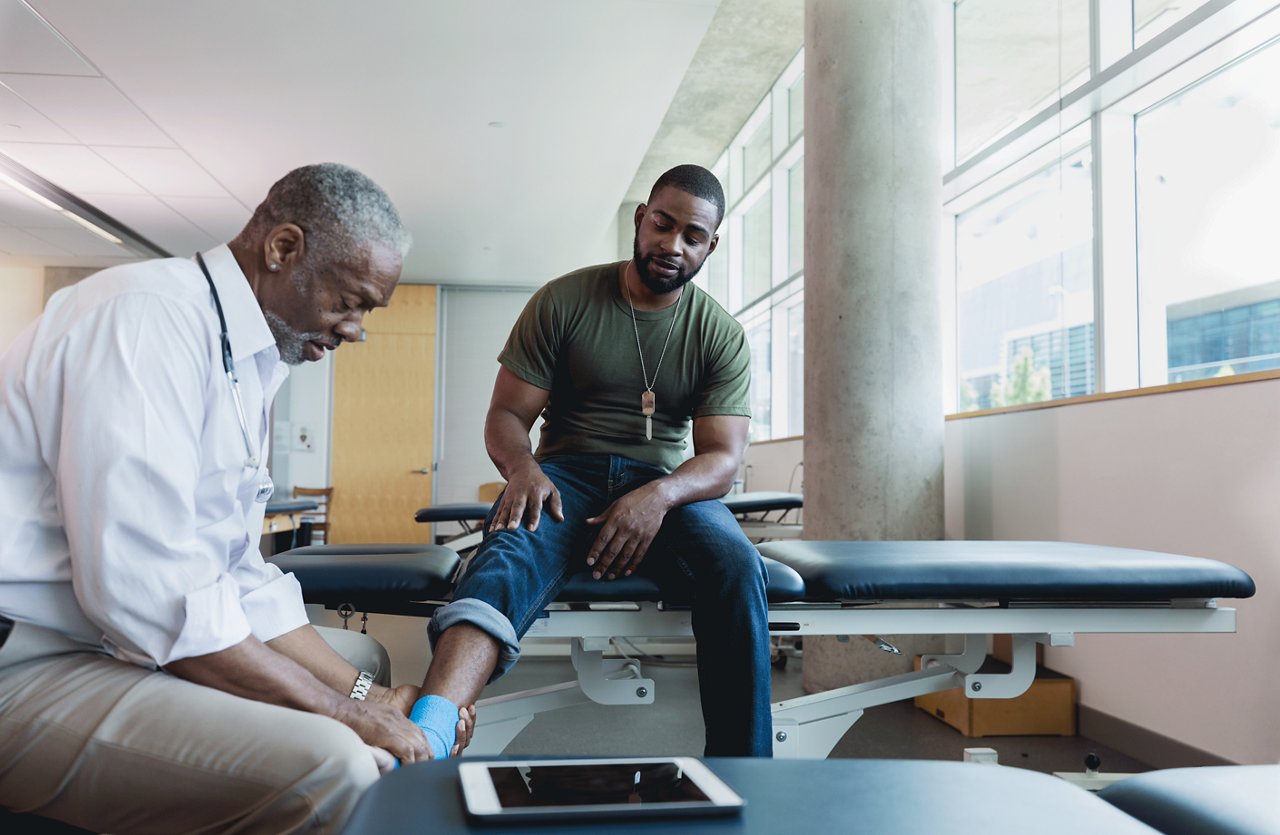 A doctor wrapping the ankle of a veteran.