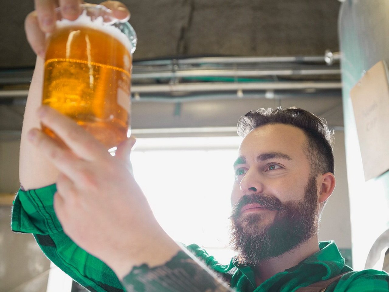 Brewer inspects beaker of beer for clarity