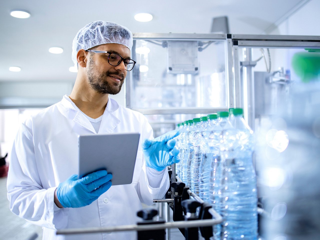 Trabajador en fábrica de embotellado revisando la calidad del agua embotellada