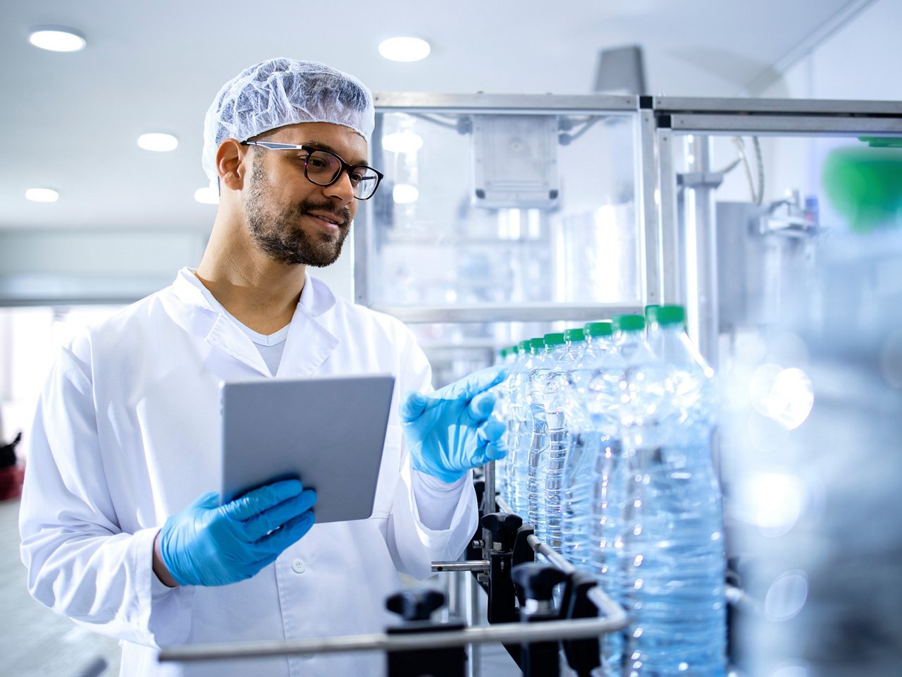 Worker in bottling factory checking quality of bottled water