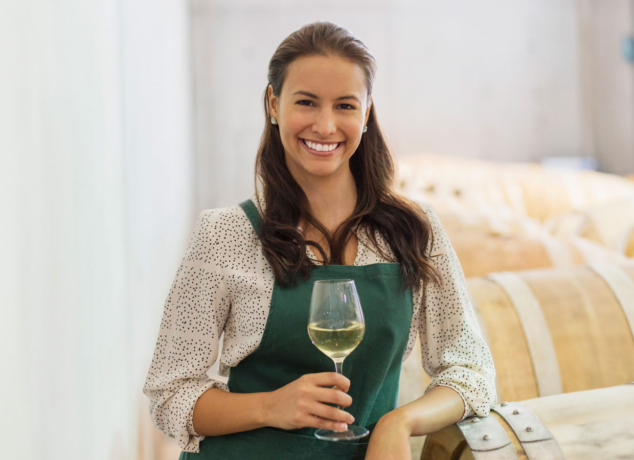 Portrait of female vintner holding glass of white wine