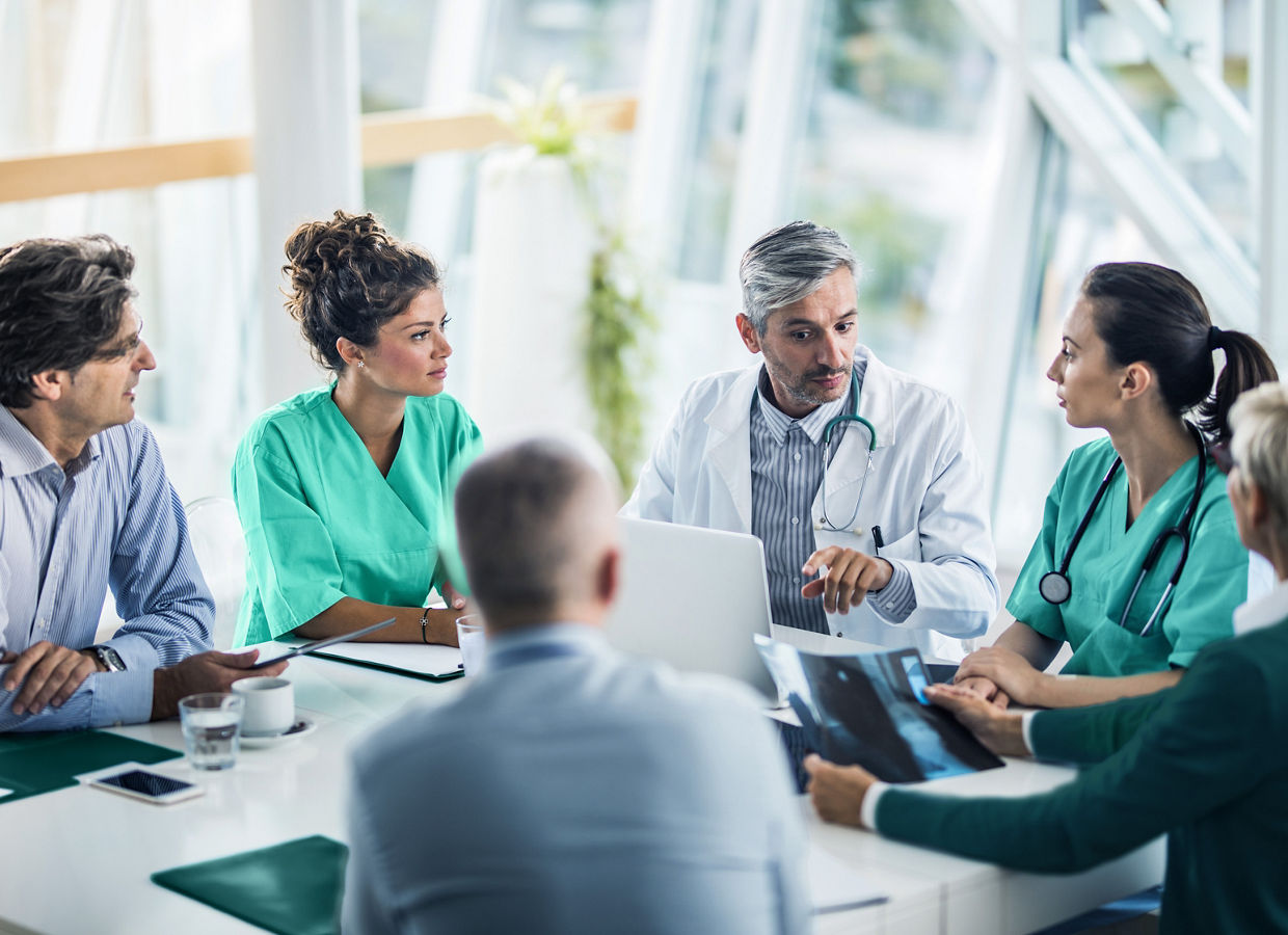 This Getty stock photo has been retouched to reflect the Solventum brand. Photo of a medical team collaborating with healthcare professionals and administrators in a conference room. A male physician is leading the discussion.