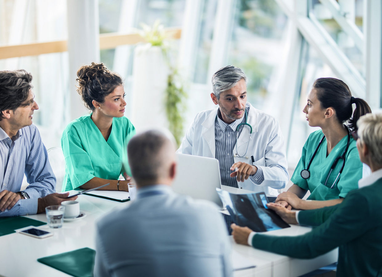 Ein medizinisches Team, das mit Gesundheitsverwaltern in einem Konferenzraum zusammenarbeitet.
