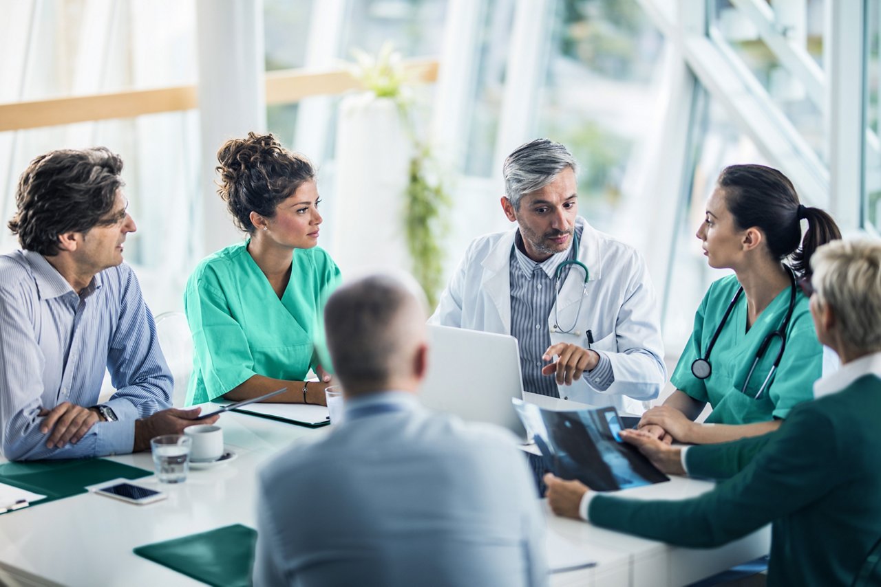 Un equipo médico colaborando con administradores de salud en una sala de conferencias.