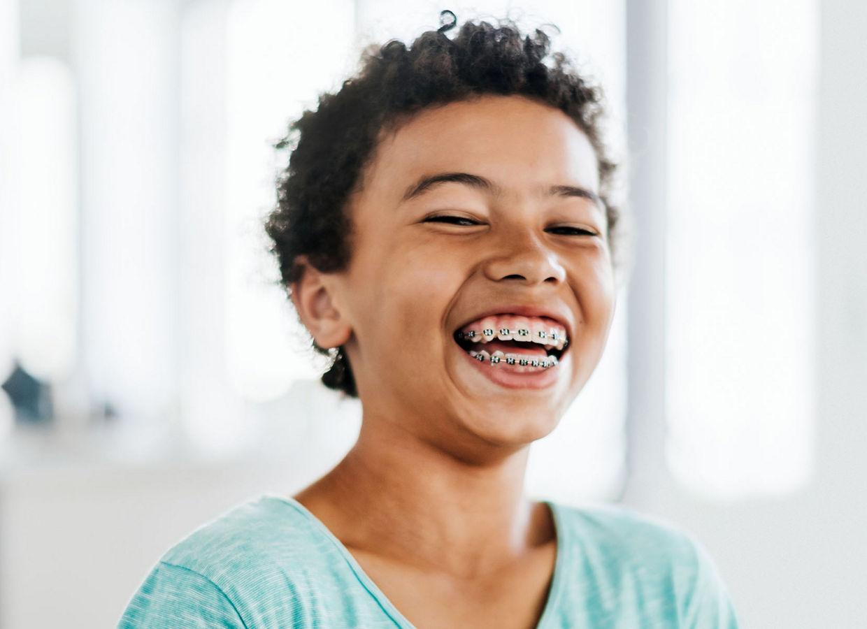 Un jeune garçon avec des accolades sur ses dents riant.