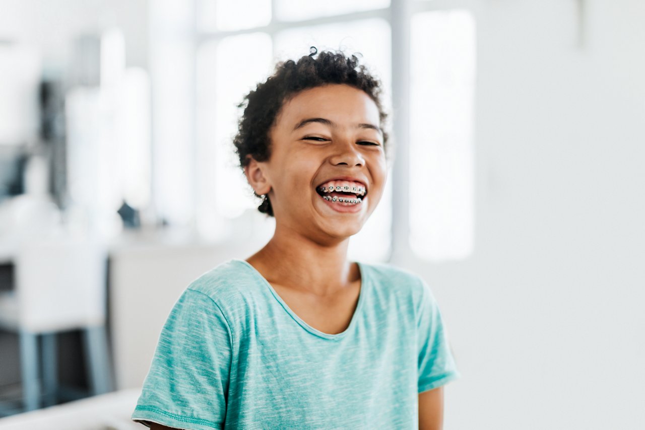 A portrait of a young boy with brace smiling at home.