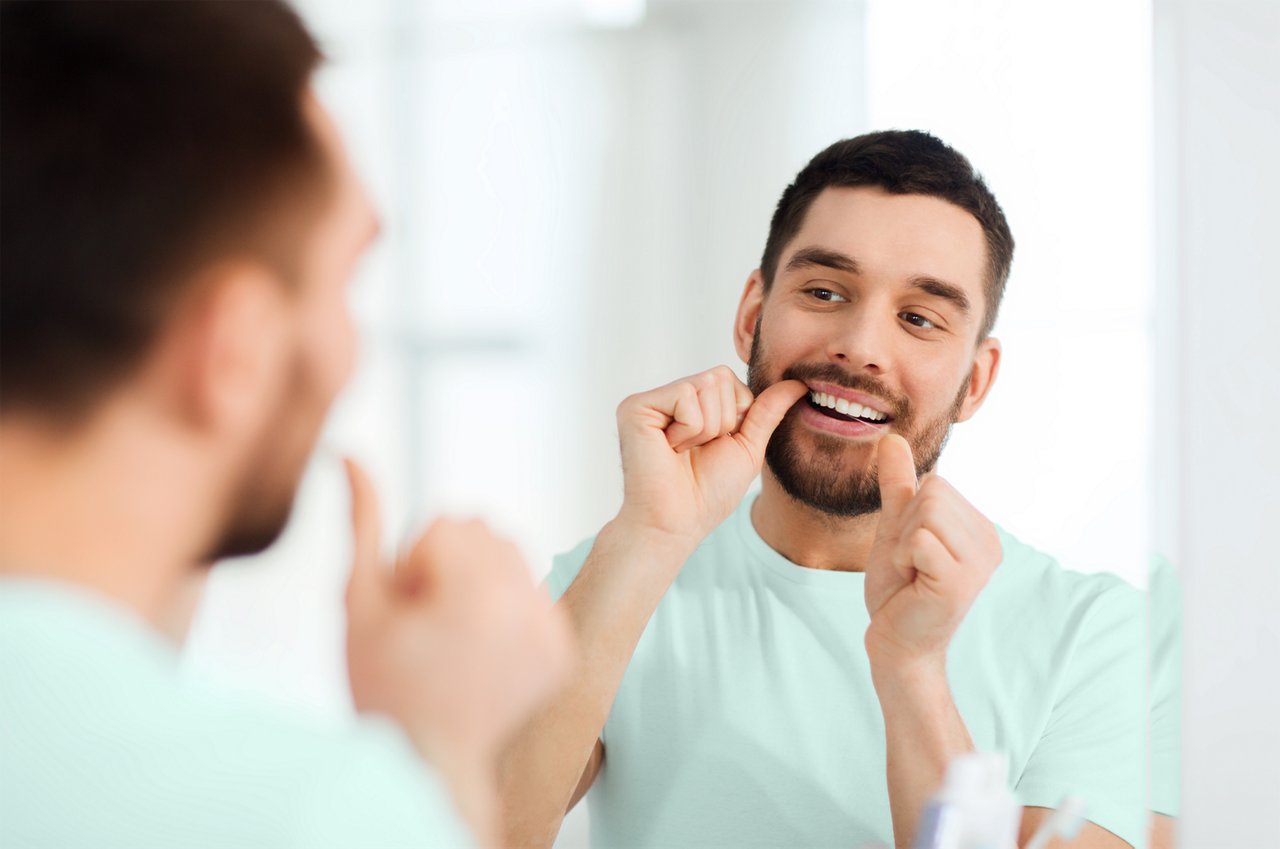 Man with dental floss cleaning teeth at bathroom, Estonia