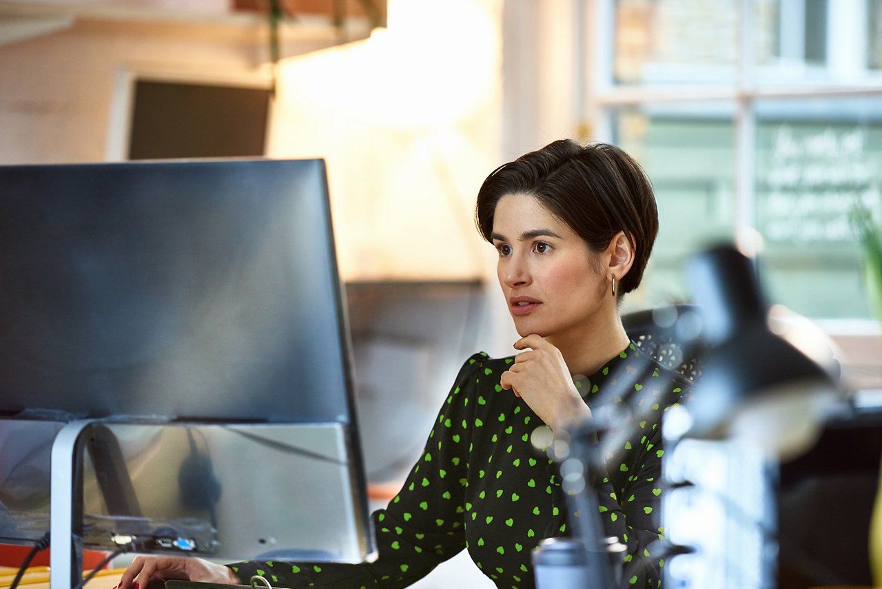 A woman sitting at a desk looking at her monitor.