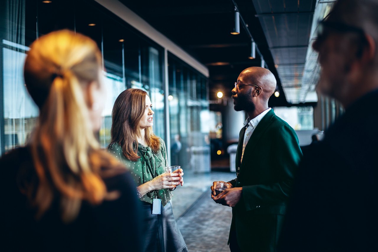 Group of four colleagues networking in an office lobby.
