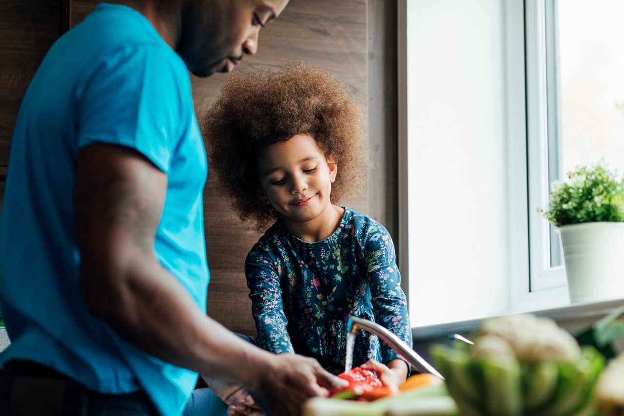 Father and young daugher washing dishes in the kitchen.