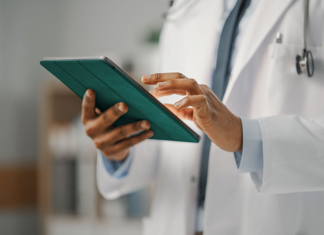 Close up of a physician viewing content on a tablet.