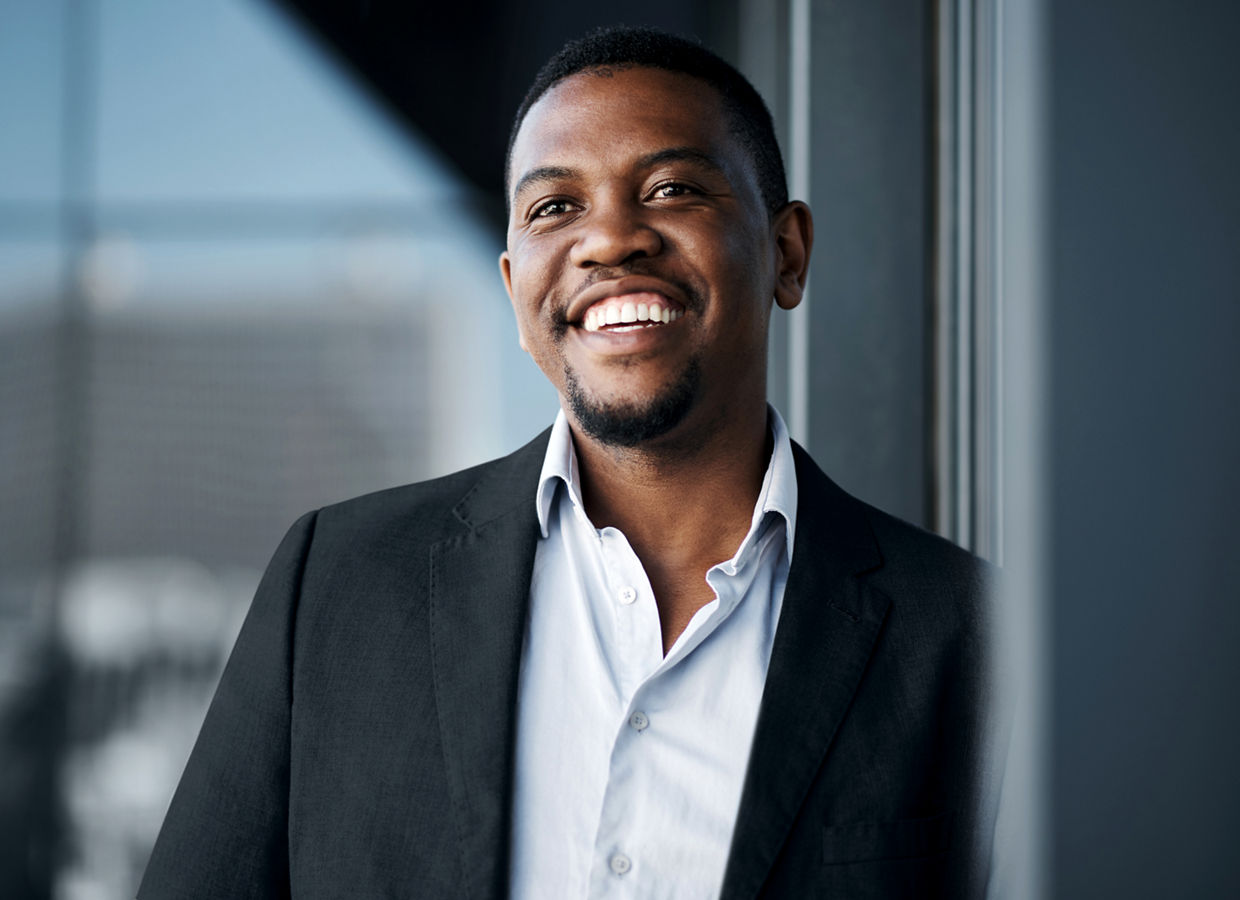 A smiling man who is leaning against a wall.