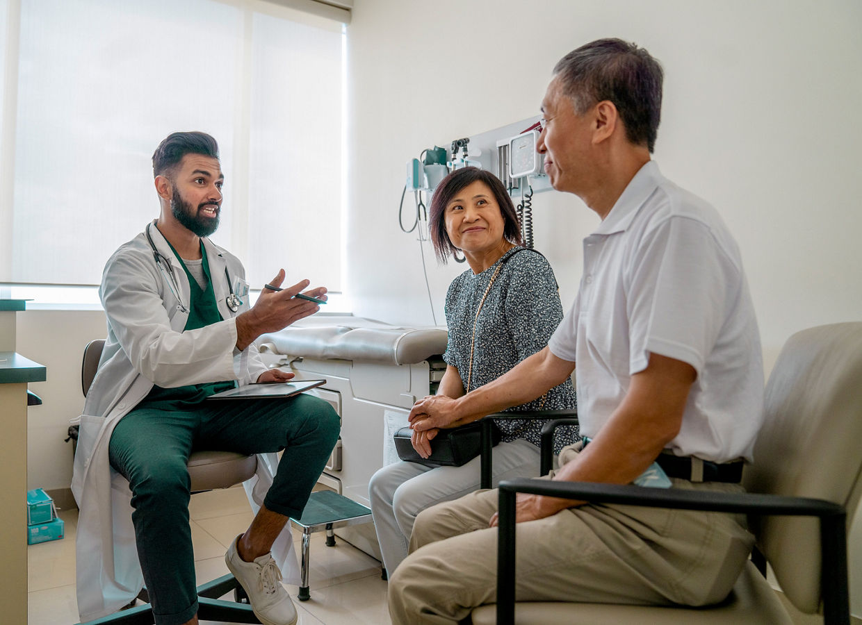 A doctor speaking to a couple in an examination room.