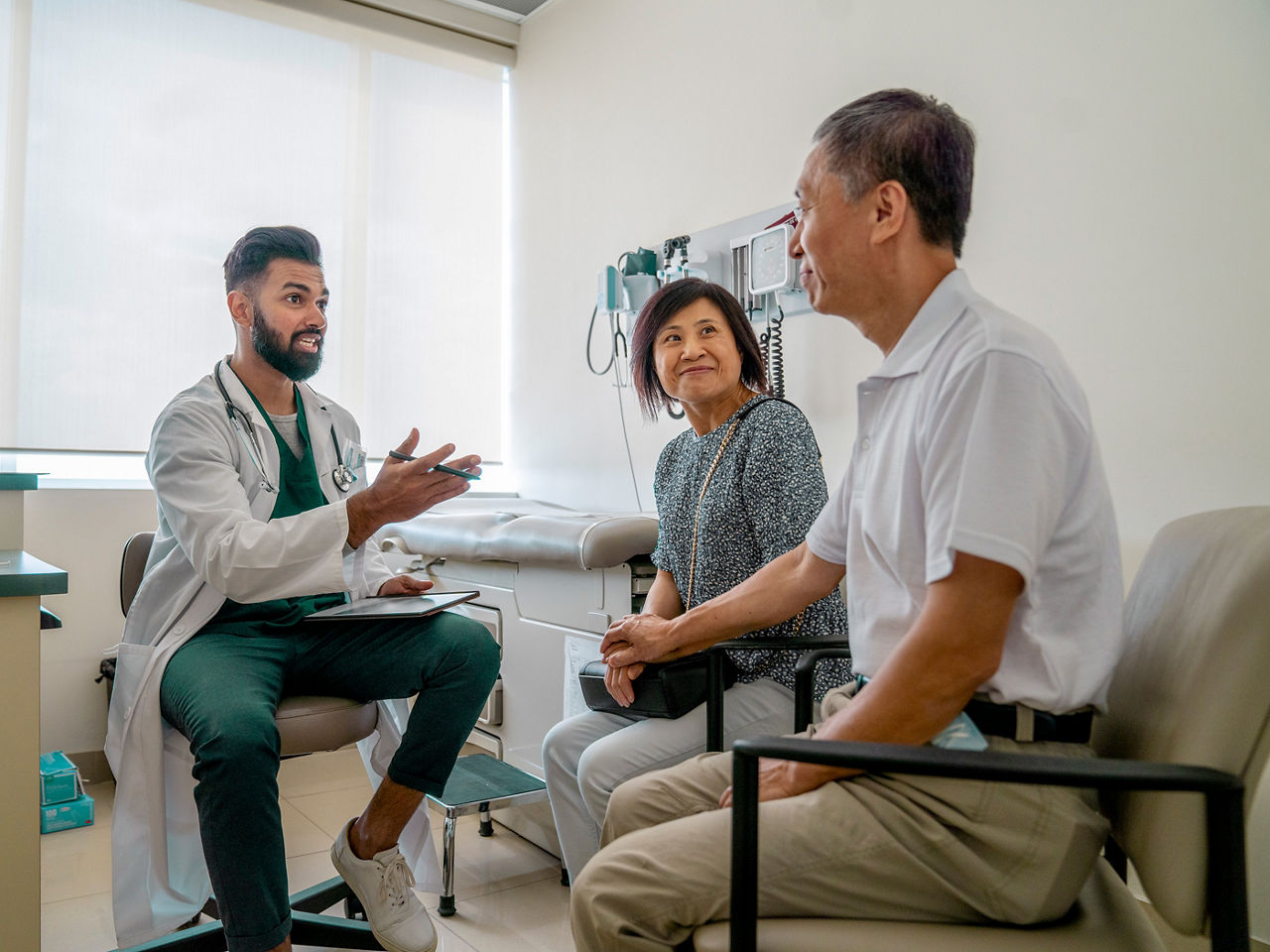 A doctor speaking to a couple in an examination room.
