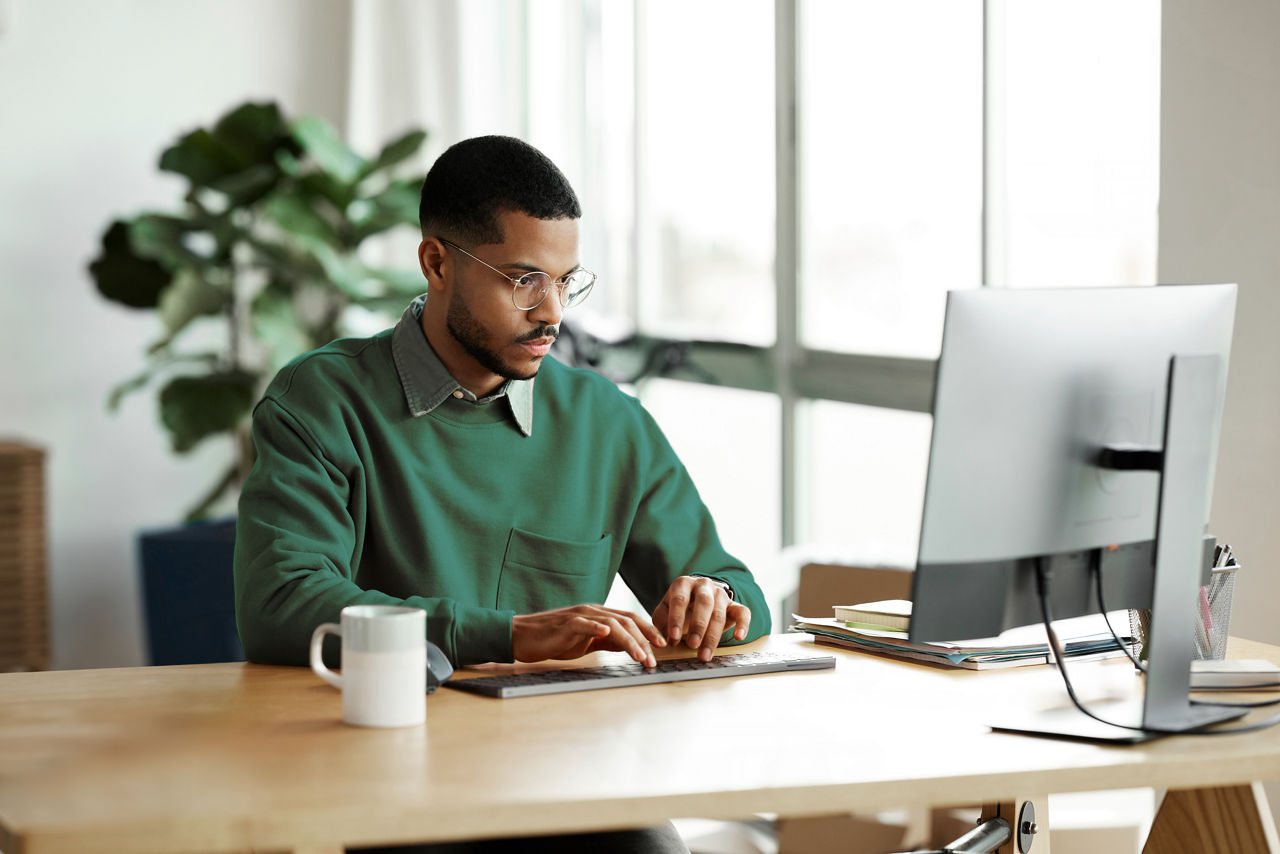 Male employee seated at his office desk while working on his computer.