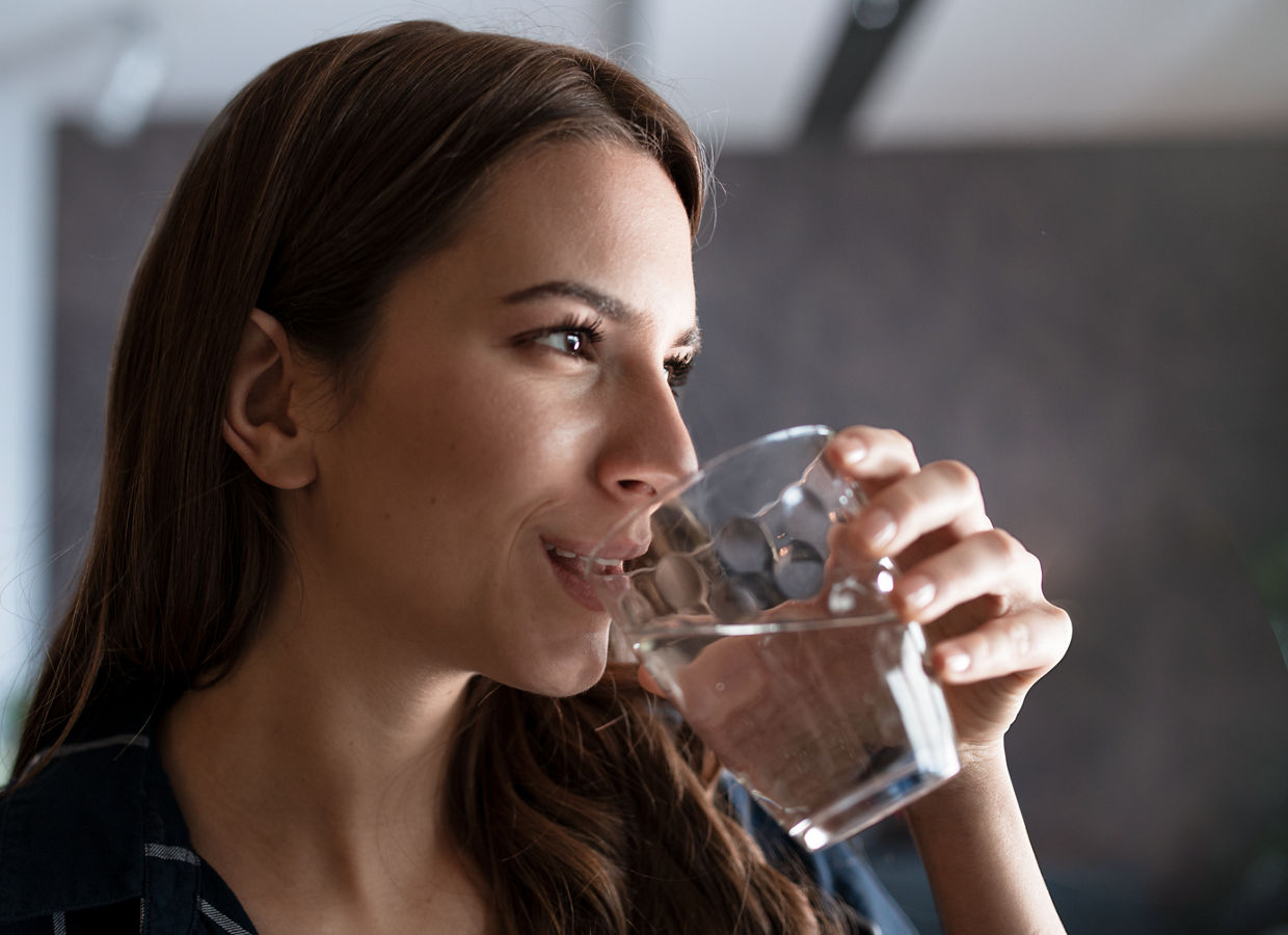 Junge Frau, die Wasser aus einem Glas trinkt