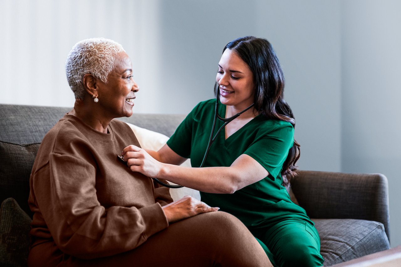 Female nurse listening to the heart of an elderly female patient