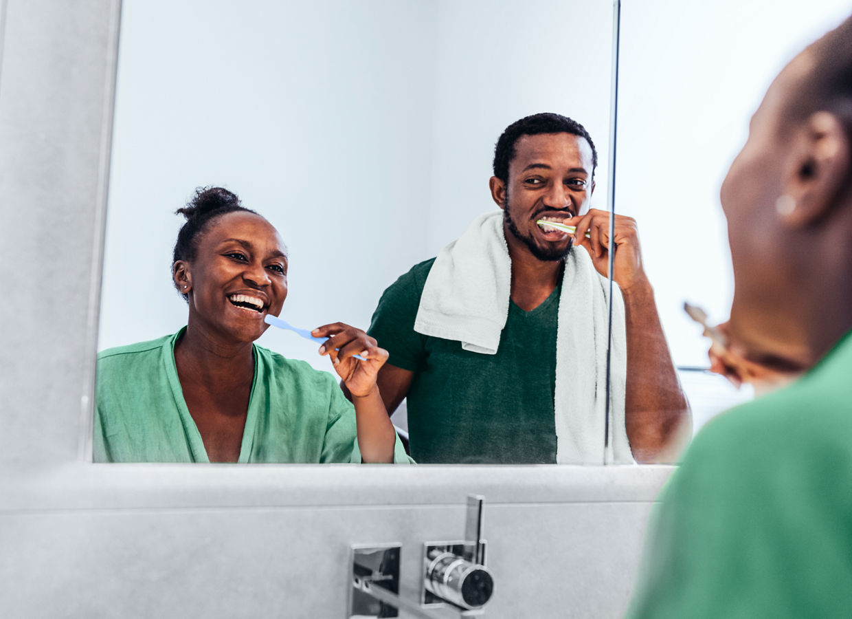 A woman and man brushing their teeth in the bathroom.