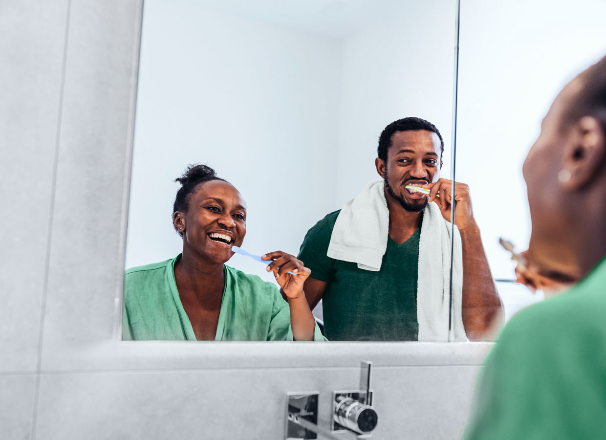 Reflection of couple brushing teeth in bathroom