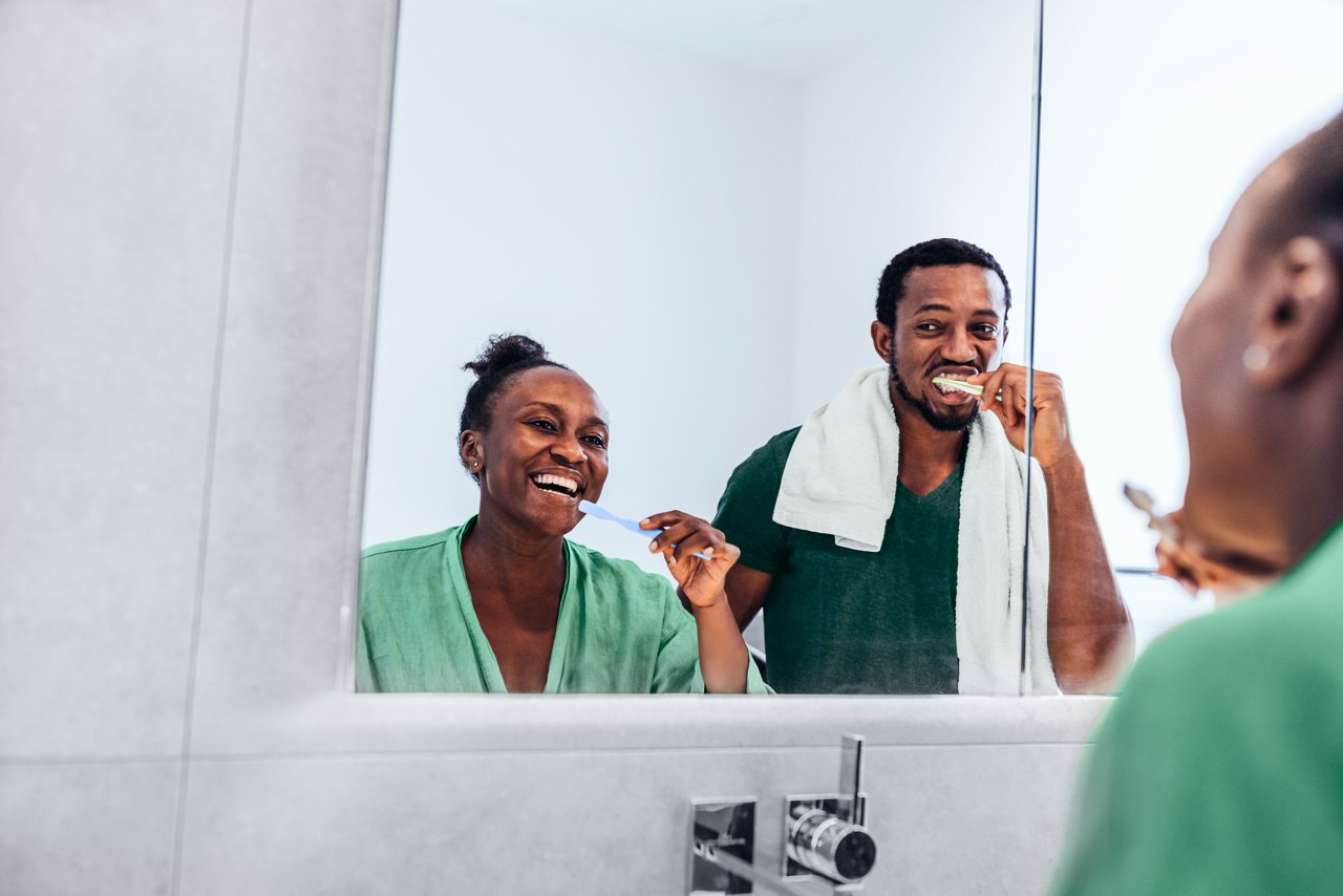 Reflection of couple brushing teeth in bathroom