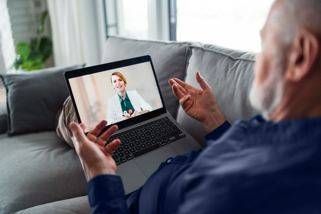 Old man speaking to doctor from home, telemedicine concept.