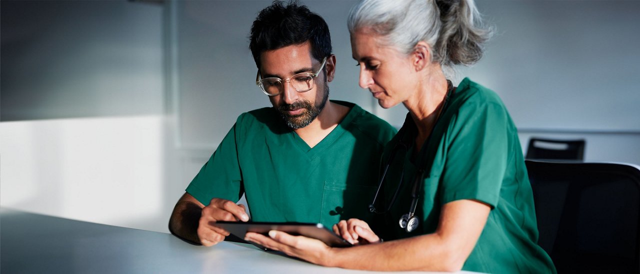 Two clinicians looking at a tablet screen.
