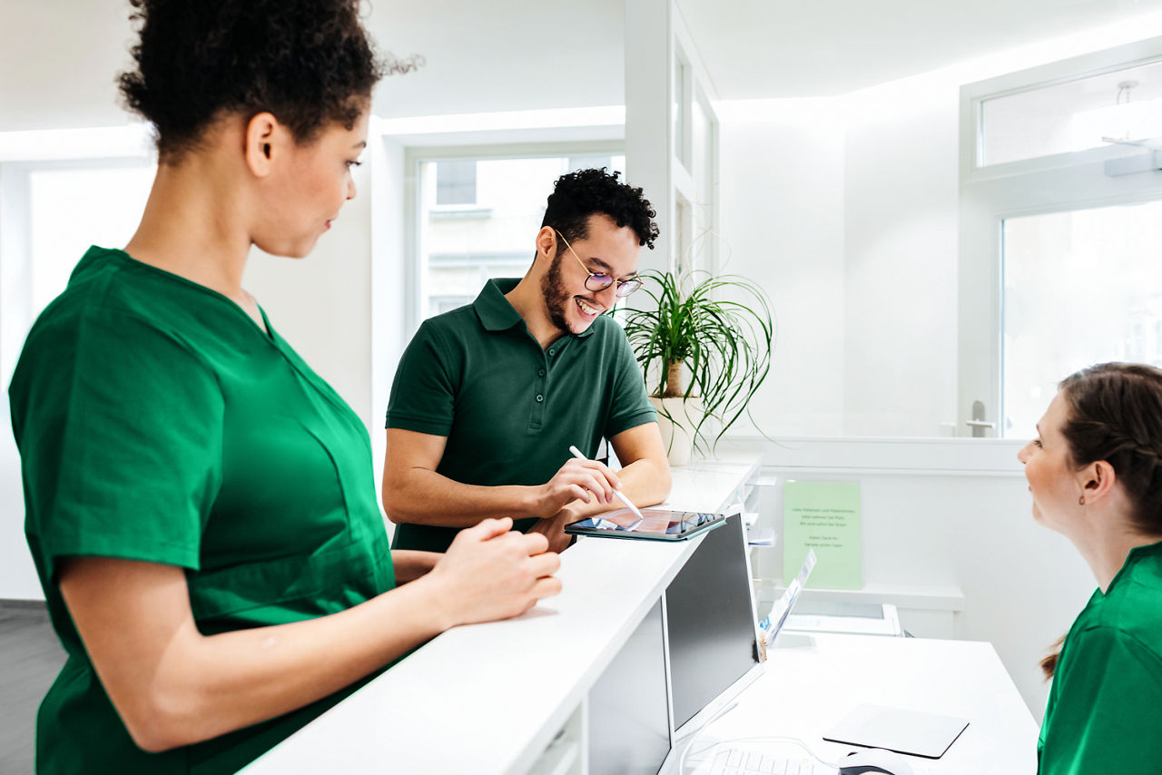 Dos administradores del hospital interactuando con una enfermera en el área de facturación del hospital.