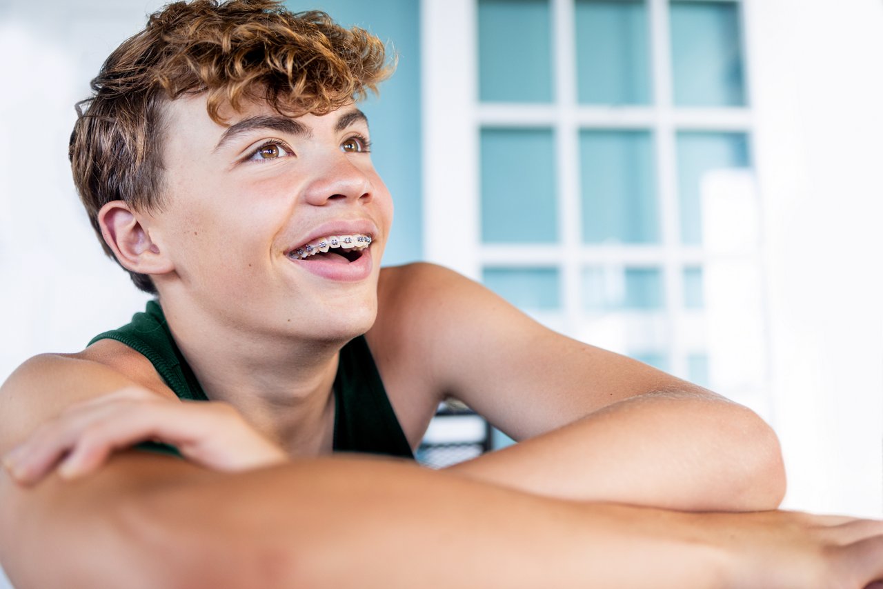 A teenage boy at home wearing braces smiling.