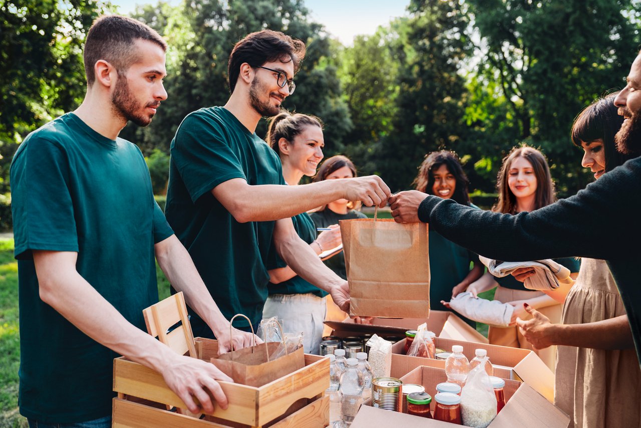 Voluntarios jóvenes entregando bolsas de agua embotellada y comida enlatada