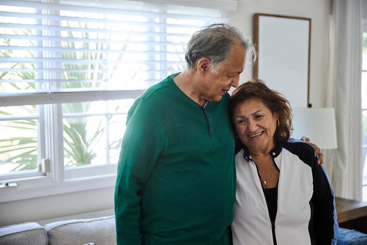 Older man comforting a woman in their home.