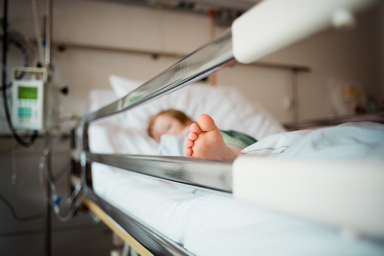 The bottom of the foot of a young child sleeping in a hospital bed.