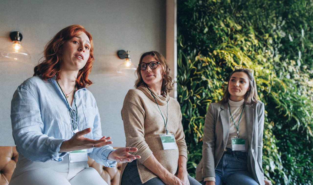 Three middle-aged woman, one of them pregnant, having a conversation.