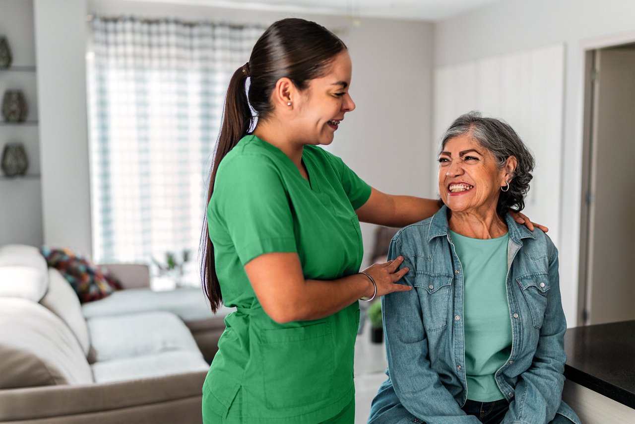 Female homecare nurse comforting a female patient.