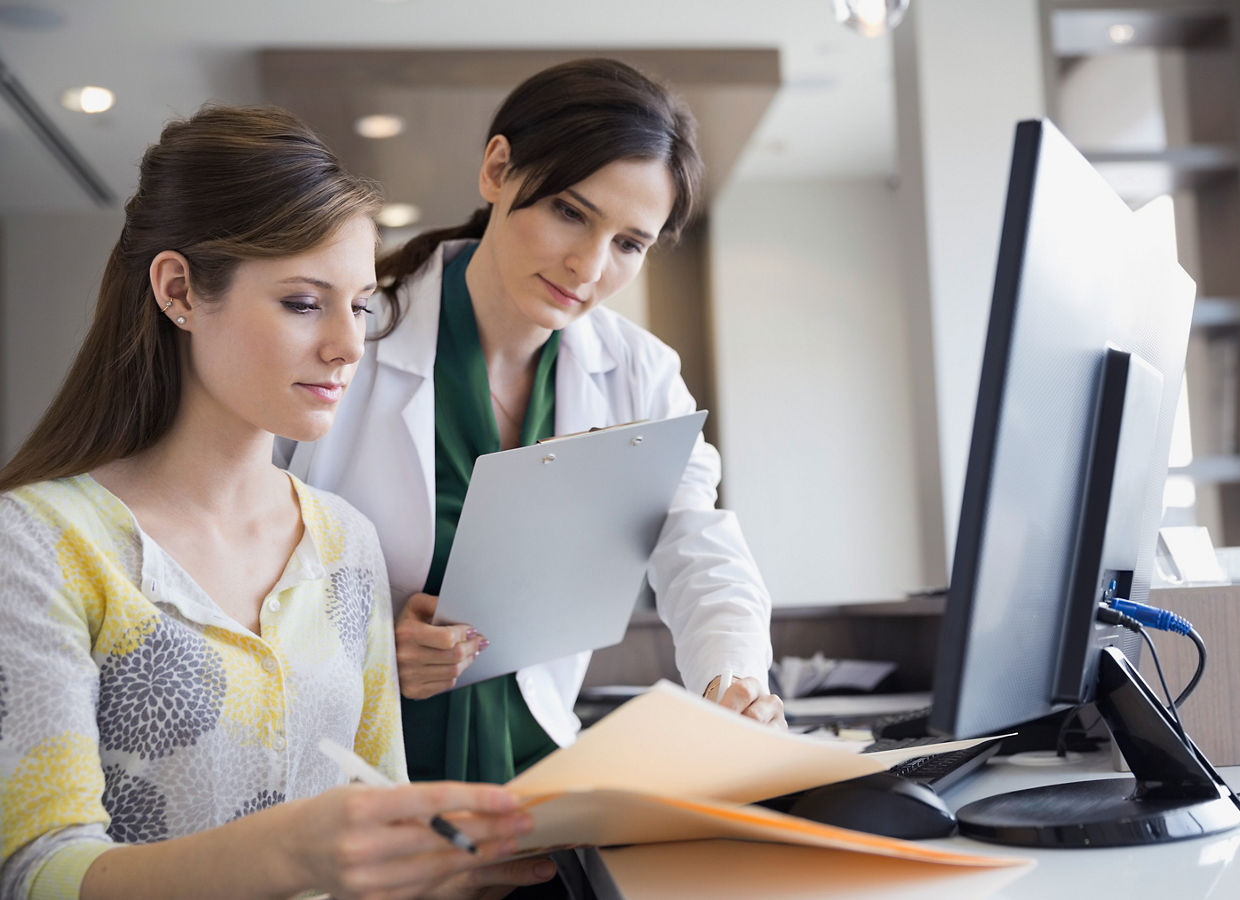 Een klinisch specialist met een schrijfblok die dossiers doorneemt met een administrator.