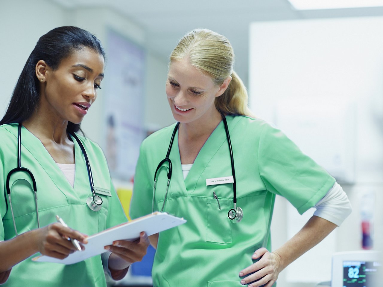 Two female clinicians looking at a file on a clipboard.