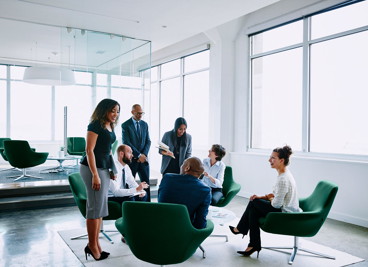 Image of several business professionals interacting in an open office setting.