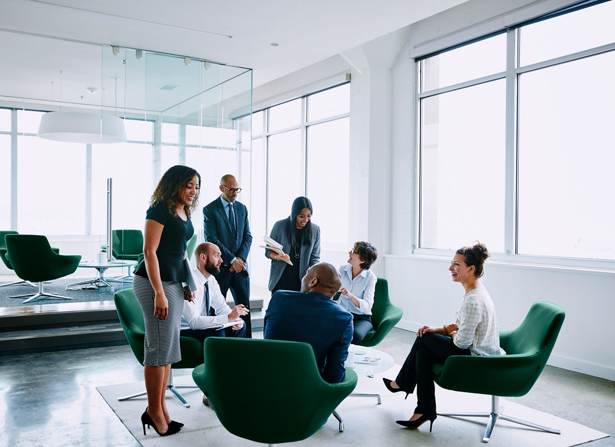 Immagine di diversi professionisti aziendali che interagiscono in un ambiente di lavoro aperto.