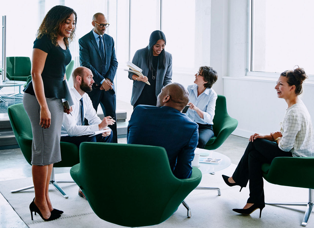 Imagen de varios profesionales de negocios interactuando en un entorno de oficina abierta.