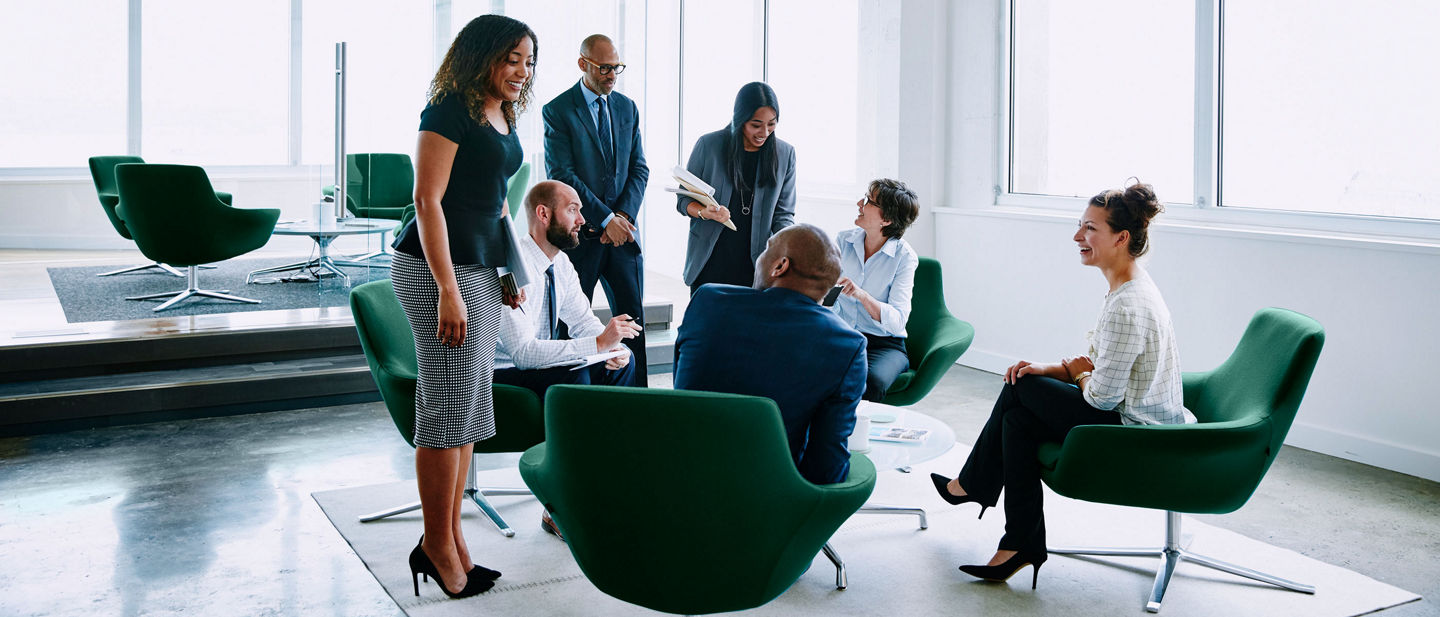 It is an image of several business professionals interacting in an open office setting.