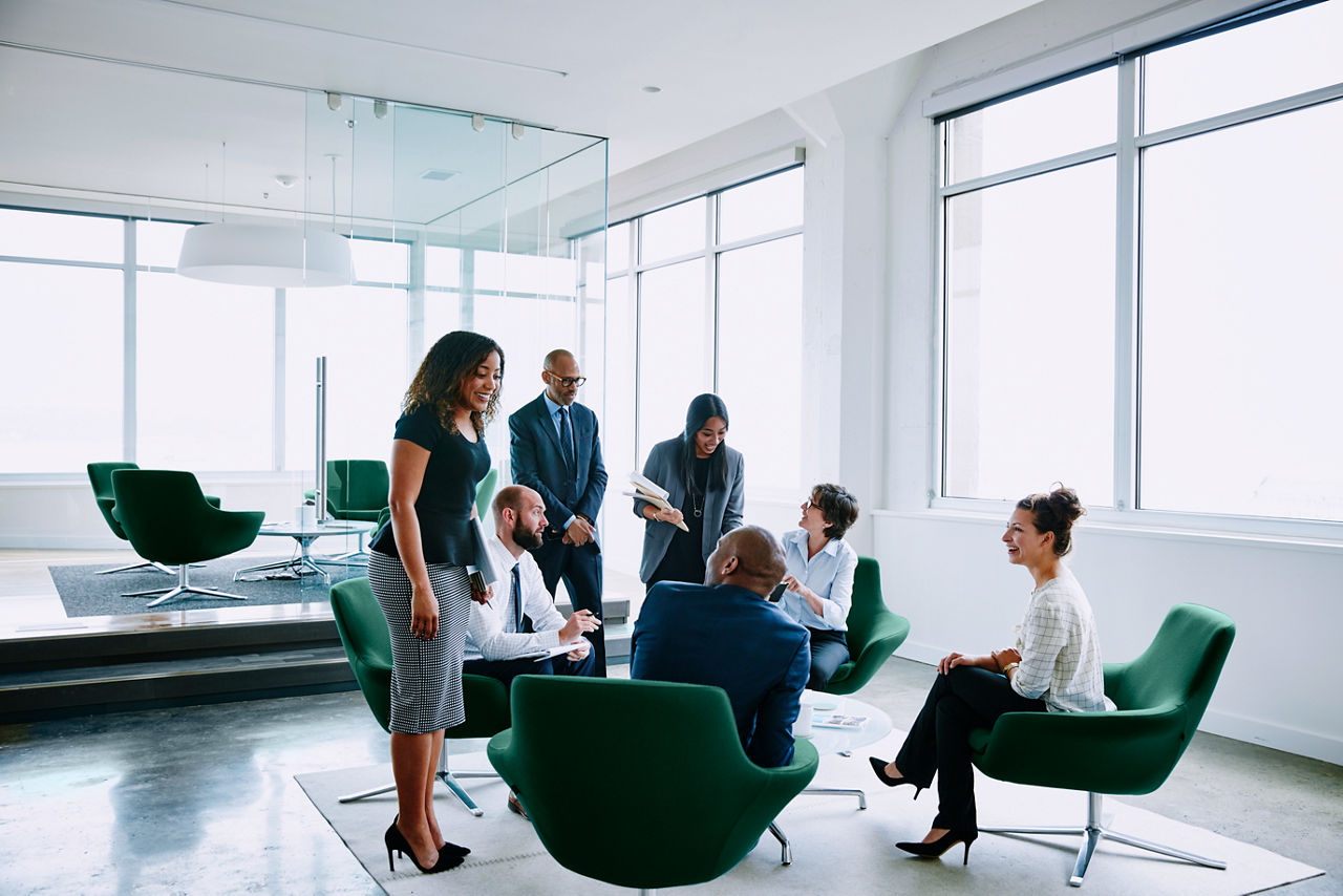 It is an image of several business professionals interacting in an open office setting.