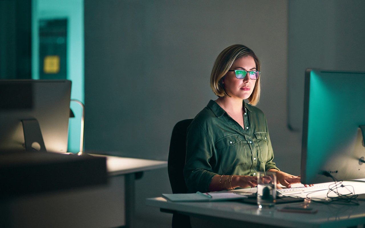 A woman typing on a keyboard in front of a computer monitor