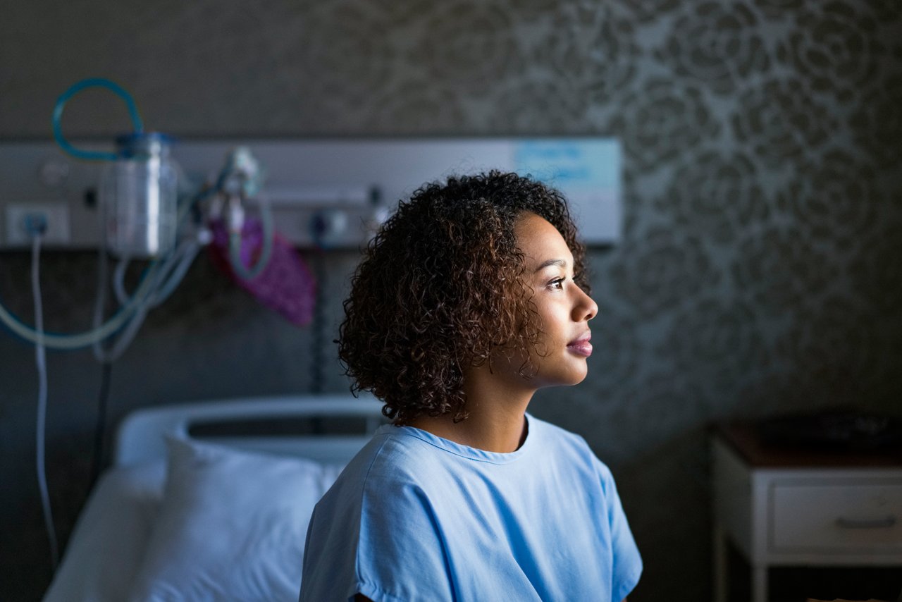A female hospital patient sitting on her bed in a hospital room
