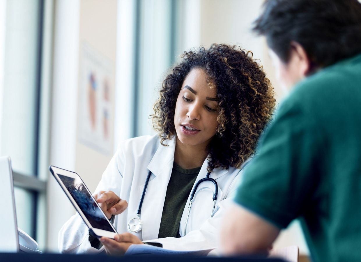 Doctor and nurse collaborating while viewing content on a tablet in a conference room.