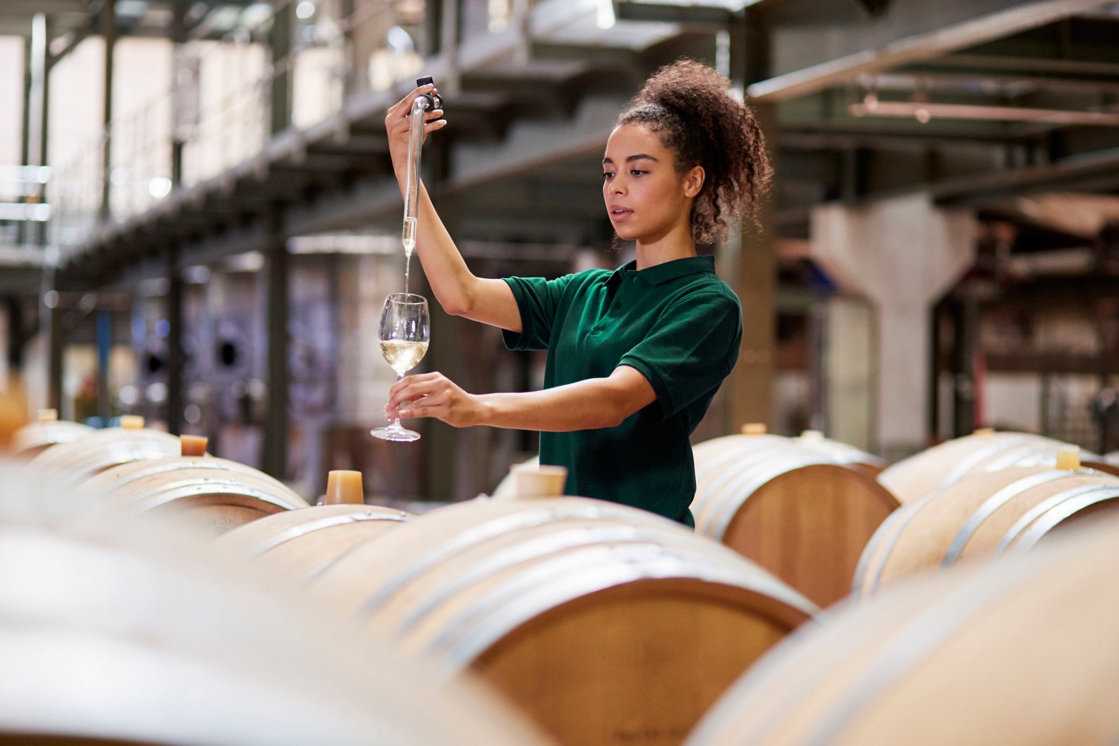 Young woman testing wine in a wine factory warehouse